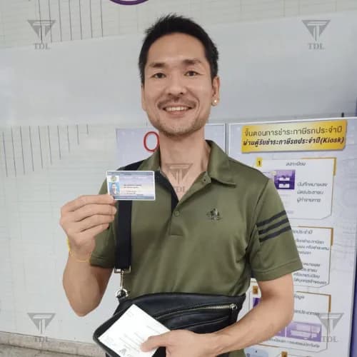 Client in green polo holding new Thai driving license
