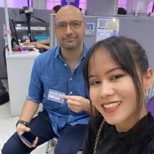 European client with Thai staff at DLT counter, proudly holding new driving license