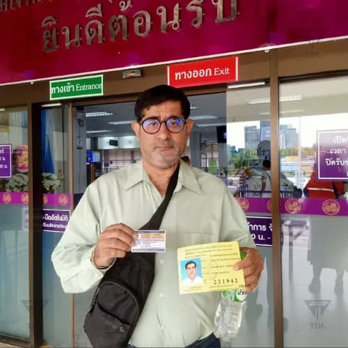 Happy client outdoors showing Thai driving license
