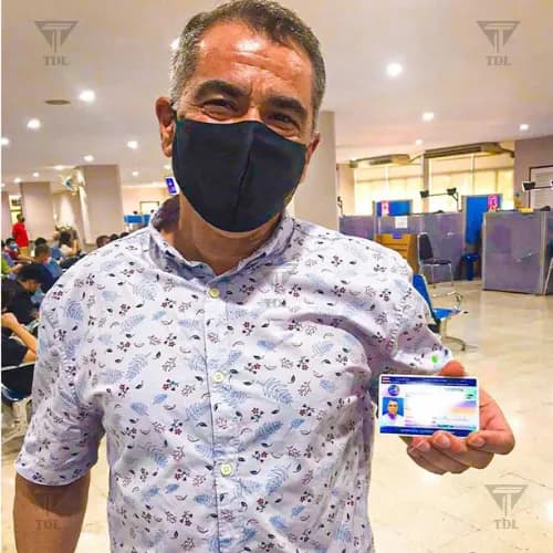 Client in floral shirt proudly showing Thai driving license