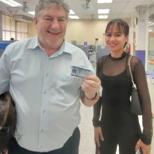 Older European client with Thai staff member, holding new driving license