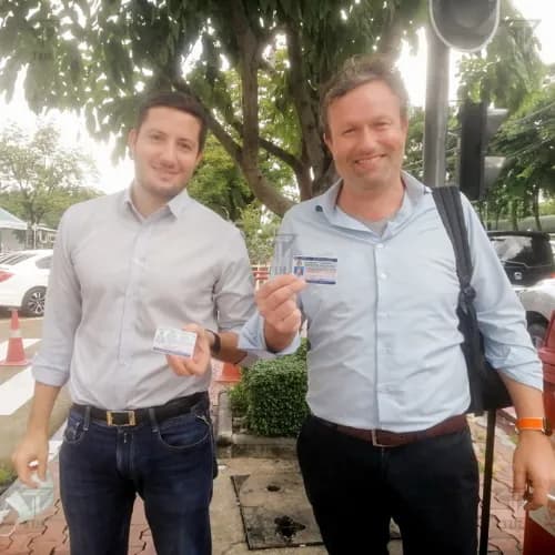 Two friends showing off their new Thai driving licenses outdoors