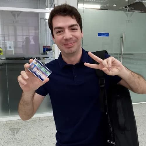 Young client giving peace sign while holding Thai driving license at DLT